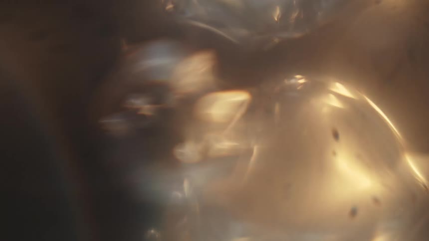Golden light and rainbow rings highlight bubbles floating and churning