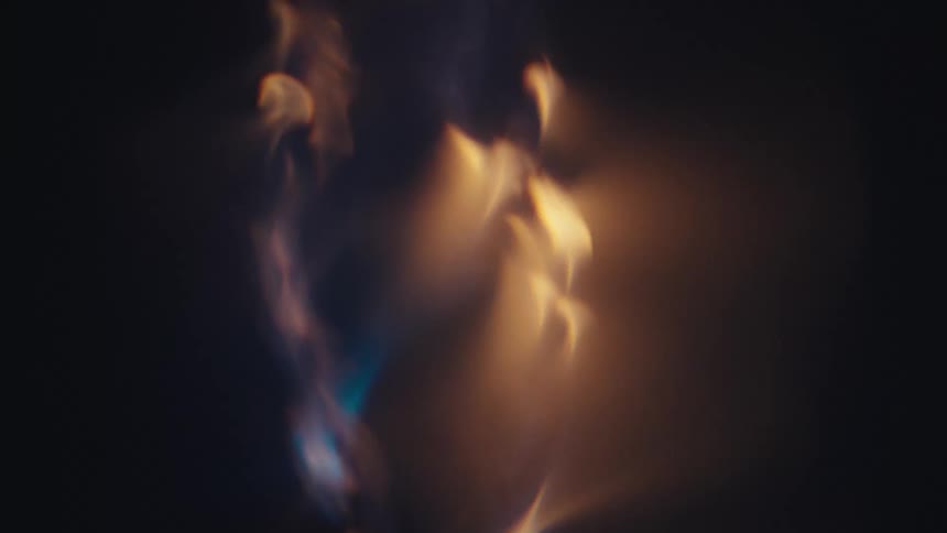 Golden light highlights vertical vortex against a dark background