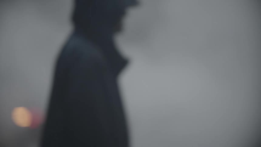 Blurred view of a street with a car on the road smoke and people walking in slow motion