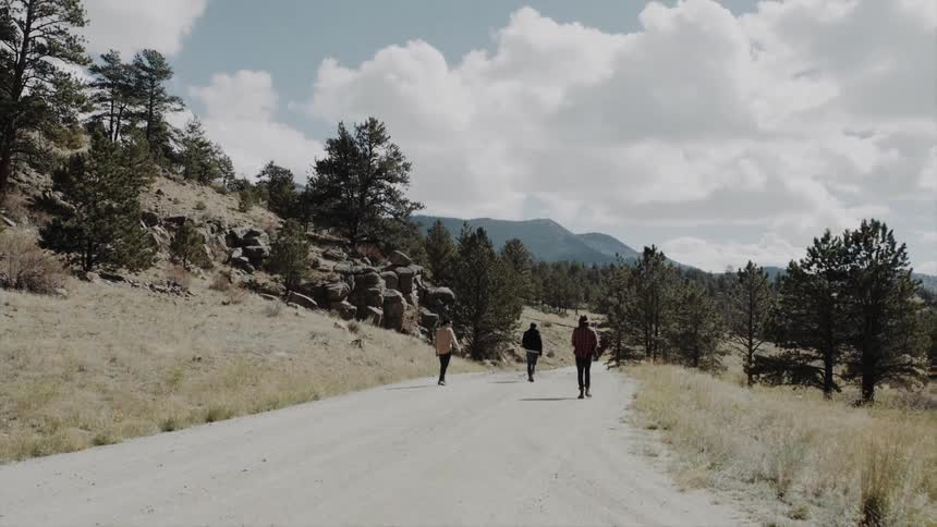 A group of friends walk on a road in the countryside