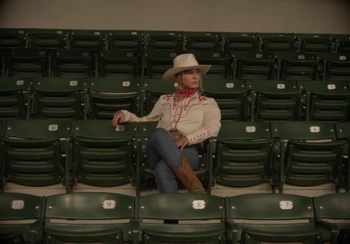 Cowgirl modeling while sitting on stadium bleacher seats