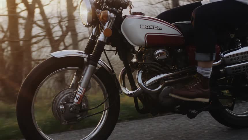Person driving a motorcycle through the countryside at evening