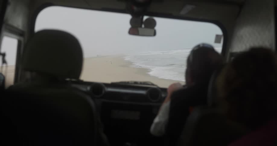 View from inside a moving vehicle on the sandy beach on a cloudy day