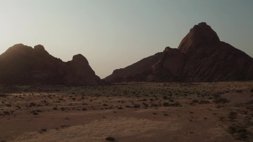 Aerial view of the sun setting behind the mountains in the desert