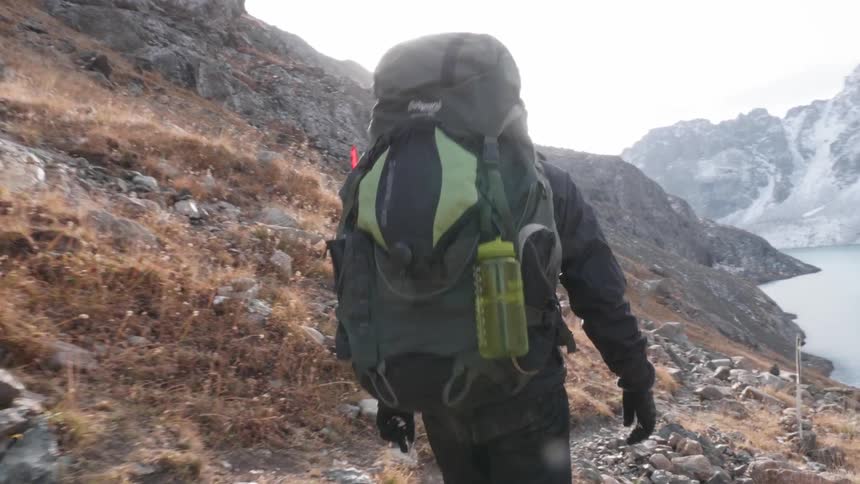 Man with heavy backpack walking on mountain path on a sunny day