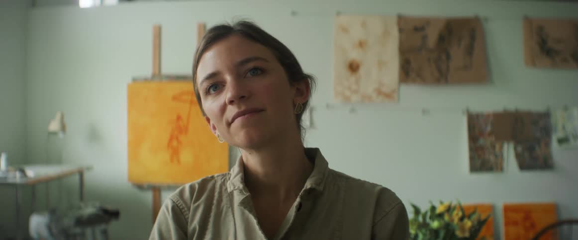 A woman is smiling as she views artwork