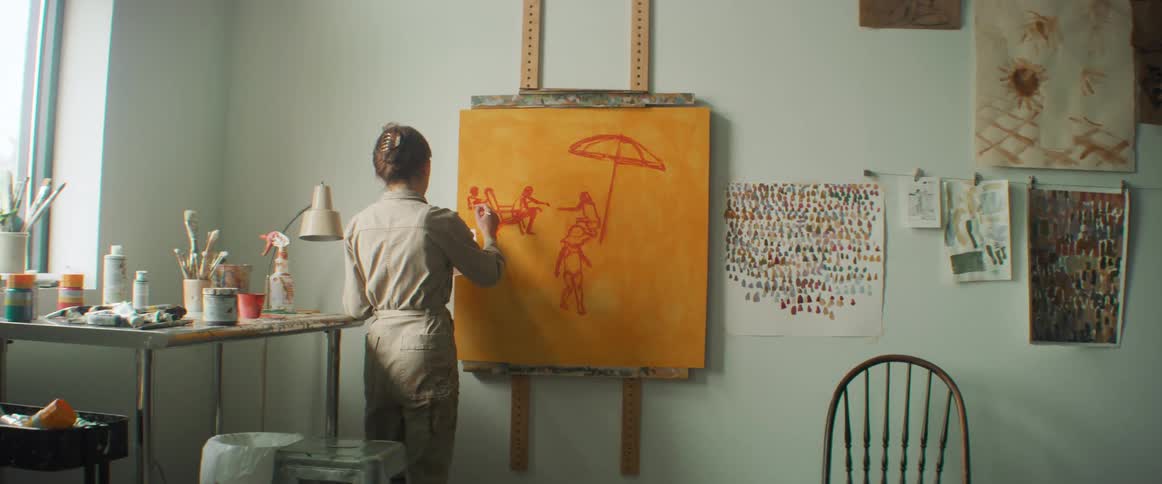 Lady drawing on the board hanged on the wall in a room at midday