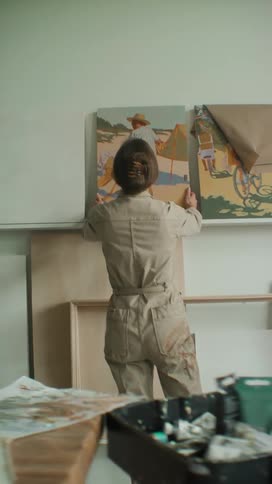 Painter placing a painted canvas on a table against the wall