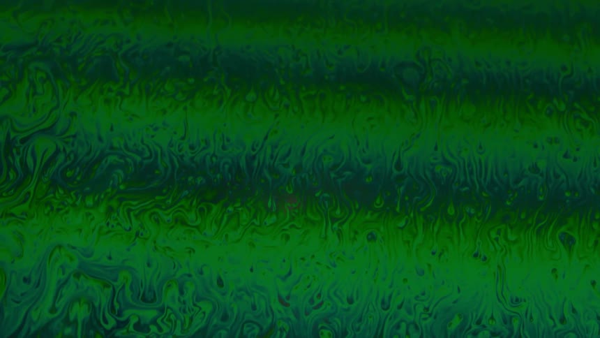 Extreme closeup of a psychedelic greenish fluid in slow motion