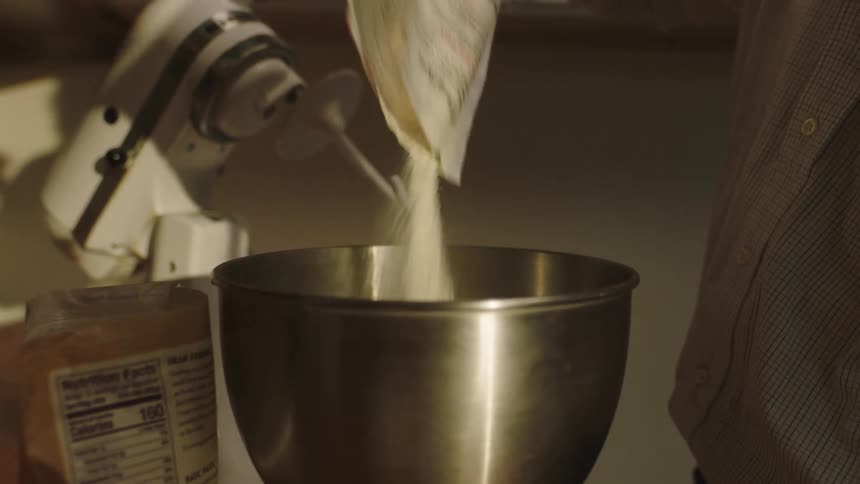 A person putting ingredients into a metal bowl