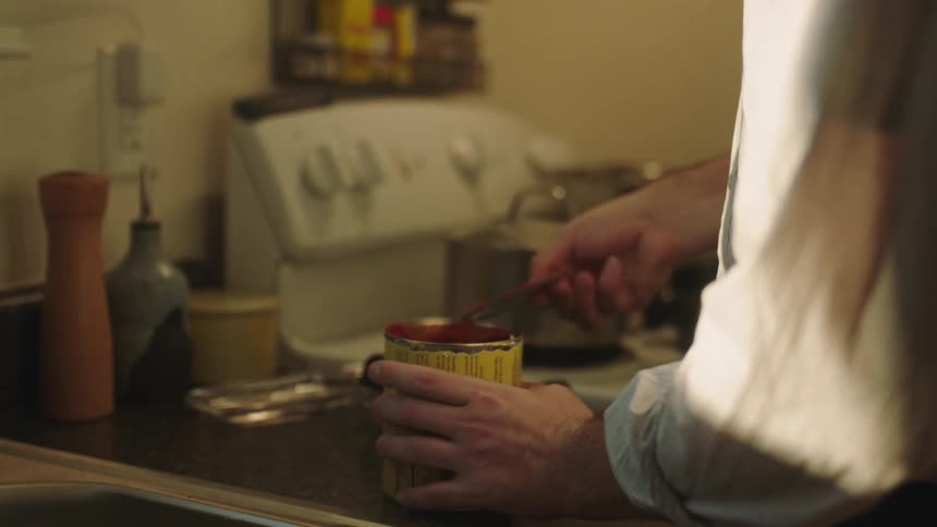 Man opening a can of tomatoes in the kitchen at home
