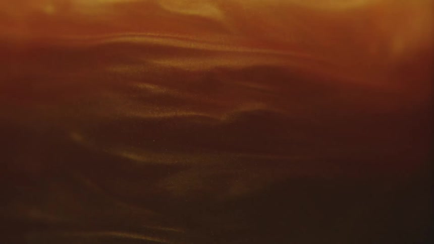 Golden and abstract liquid spiraling in slow motion