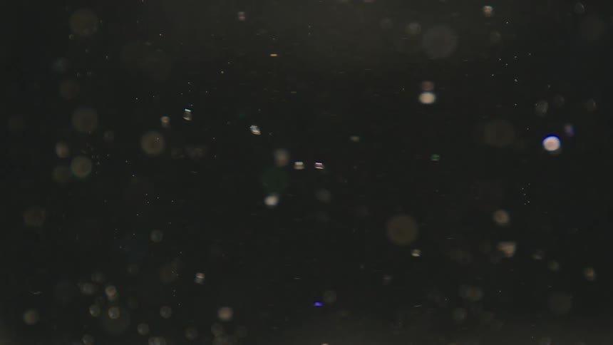 Shiny shimmering particles spinning in a clear liquid