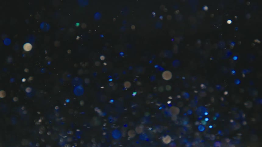 Small glittering particles drift and swirl around in the darkness