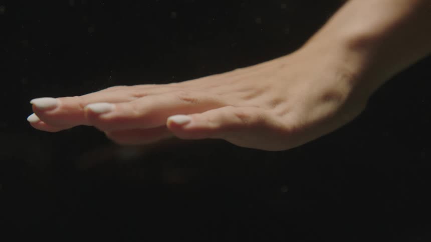 Extreme closeup of a womans hand with whitepainted nails