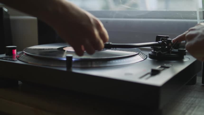 Hand placing the needle of a record player over a vinyl