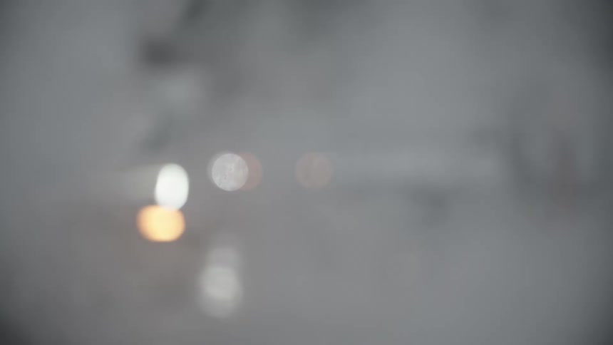 Blurry view of a city street with cars passing smoke and people in slow motion