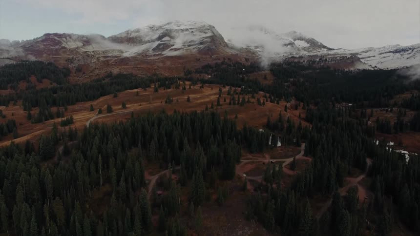 Aerial panorama of a landscape with coniferous trees and snowcovered mountain range on a cloudy day