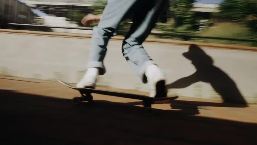 A young person jumps over stairs and skateboards down the sidewalk on a sunny day