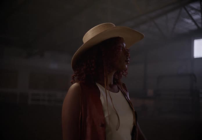 A woman running her hand over the brim of a cowboy hat