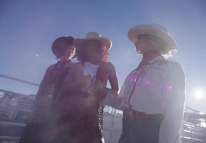 Three models wearing cowgirl outfits in the corral
