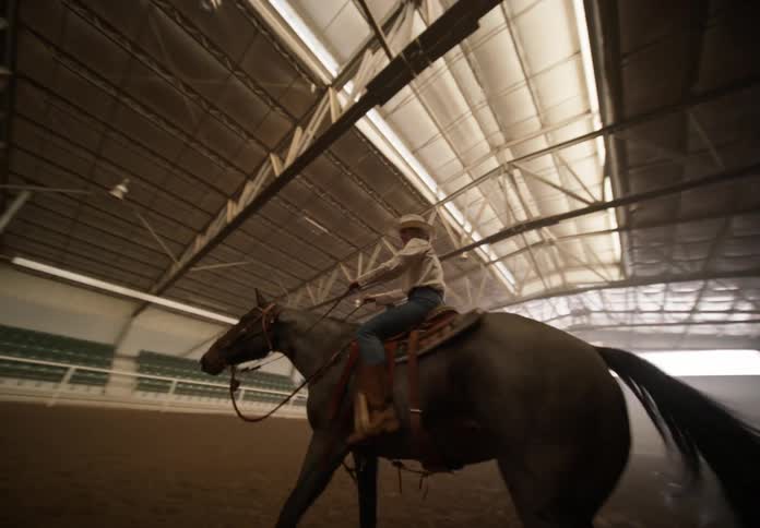 Cowgirl on horseback spinning inside an arena