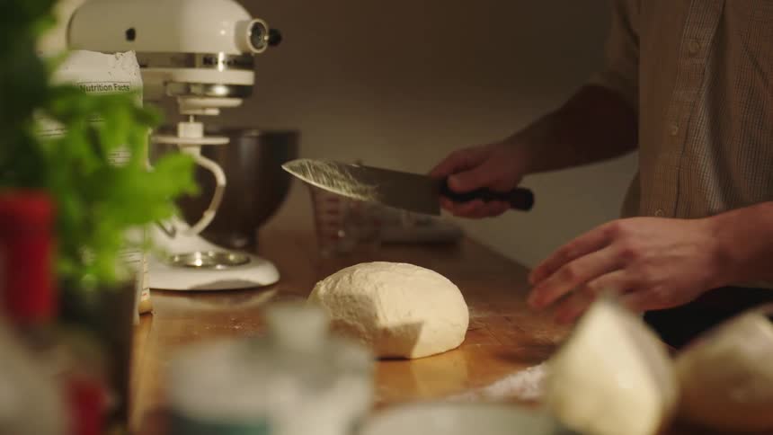 A person cutting dough made from flour on a table