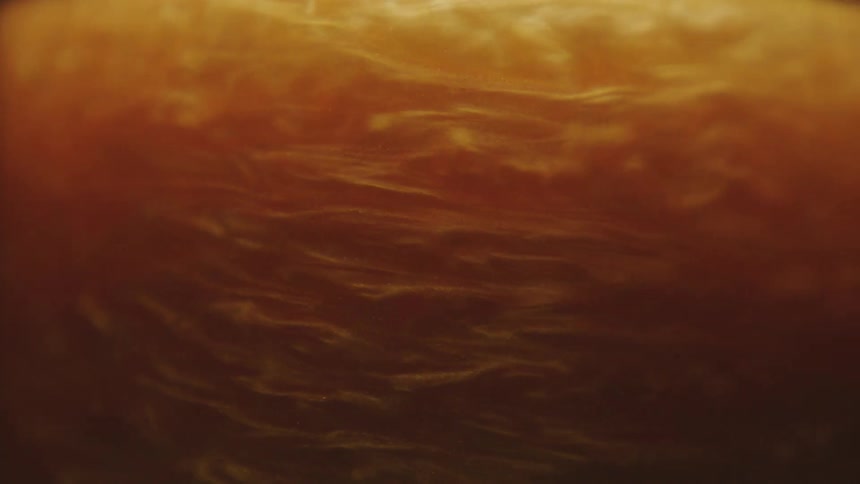 Extreme closeup of a golden liquid in slow swirling motion