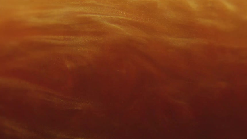 Thick amber shimmering liquid swirling