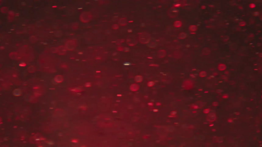 Red liquid with glimmers swirling in slow motion