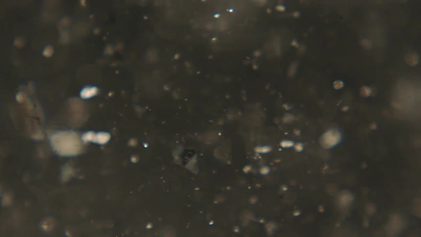 Extreme closeup of a liquid with shiny confetti in swirling and abstract motion