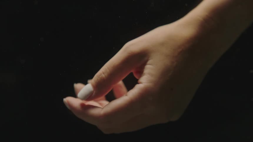 Close up of the hand of a woman against a black background