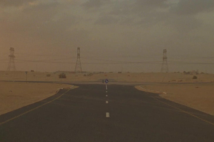 A road in the desert next to power lines