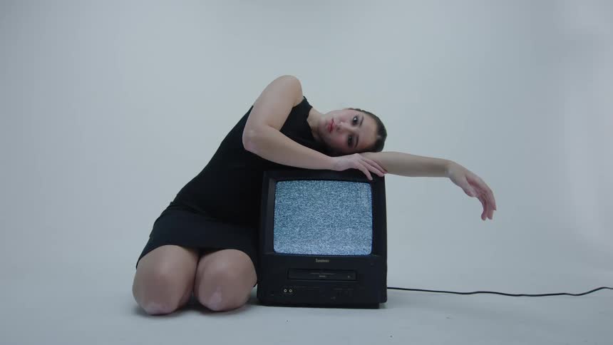 Woman on a black dress reclines on a vintage television