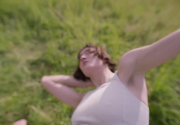 Woman with a white crop top and shorts dances in the green