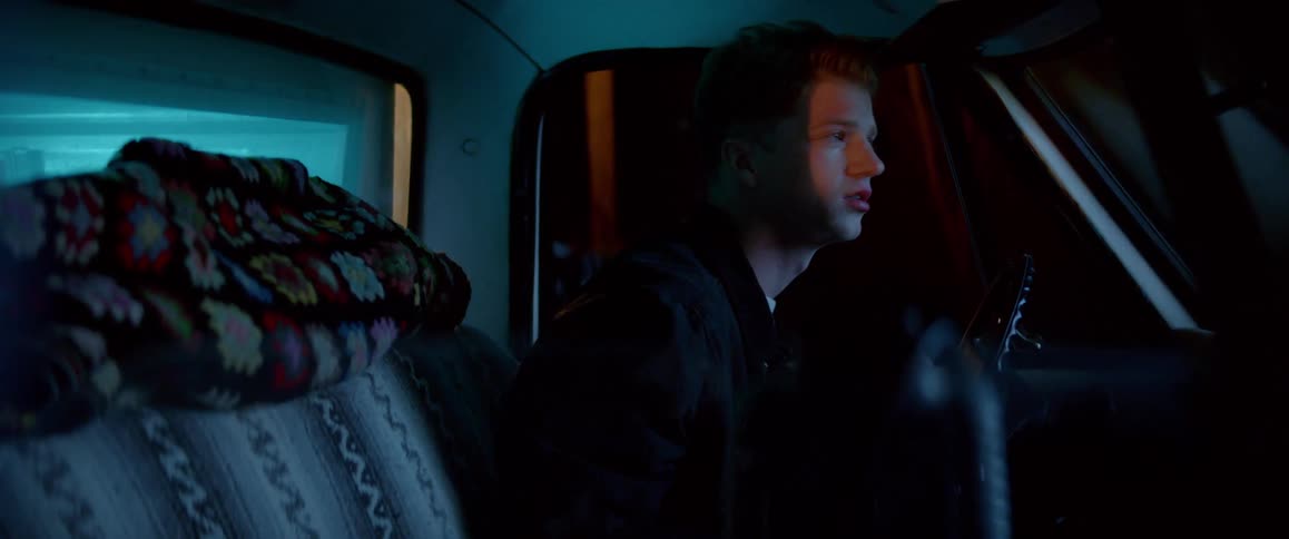 Young disoriented man sitting on a truck at night