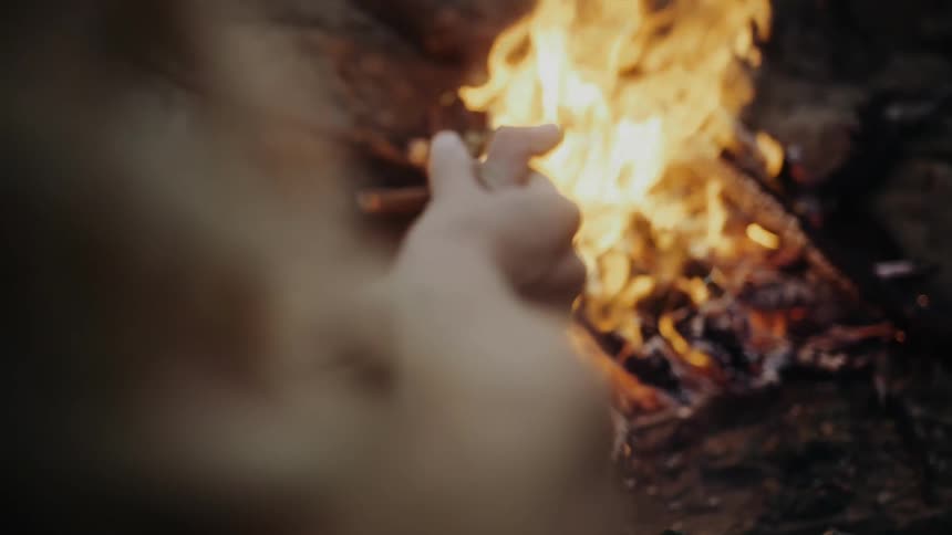 Clenched hands beside a burning fire at night
