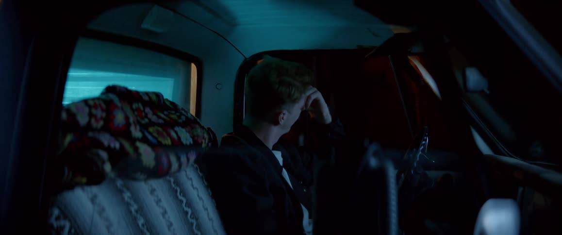 A man crying in his car on a deserted road at night