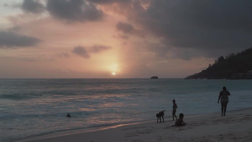 Family have fun on a beach at sunset