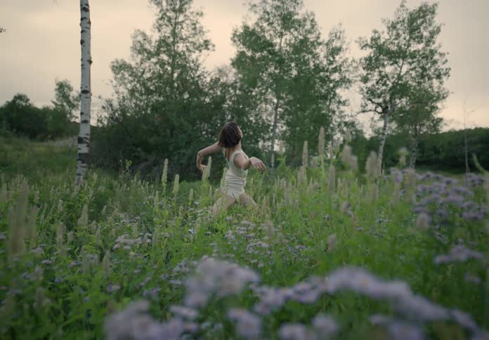 Woman dancing in a garden amidst nature in the morning