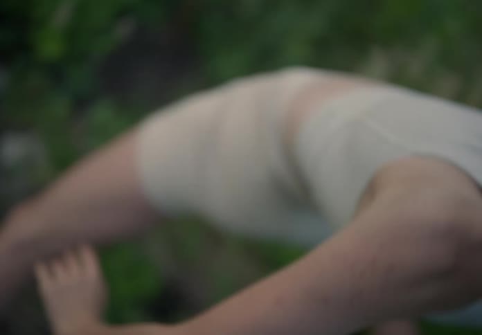 Woman with a bob hairstyle white shirt and shorts dances on green dances in the field