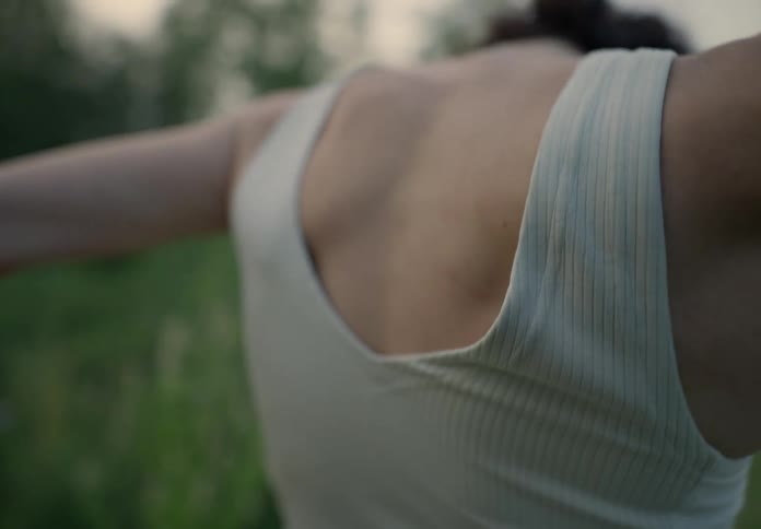 Woman dancing with her back to the camera in the midst of a field in nature