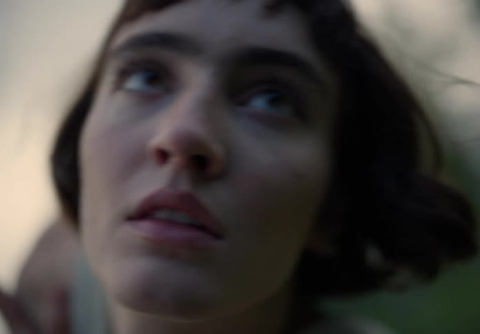 Woman with a brown bob hair dances in the green field