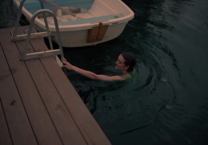 A woman swimming in a lake during sunset