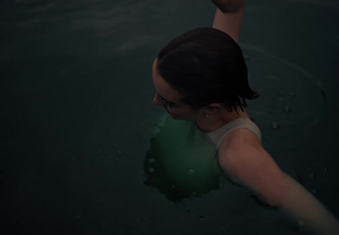 A woman is with almost her entire body underwater and she raises her arms up