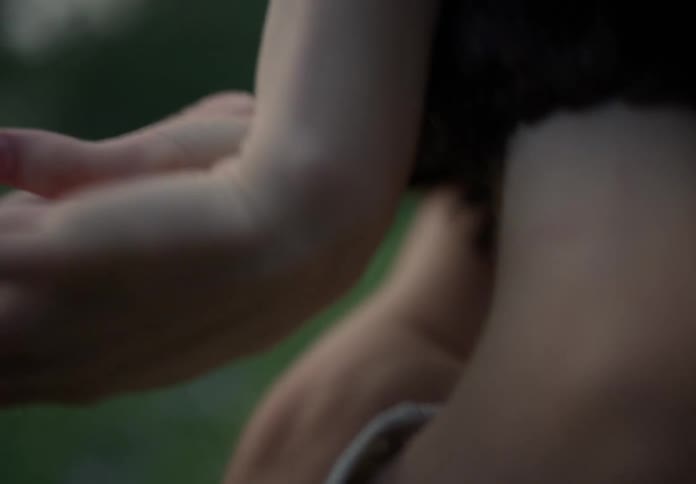 Woman with bob hairstyle and a white undershirt dances in the green field