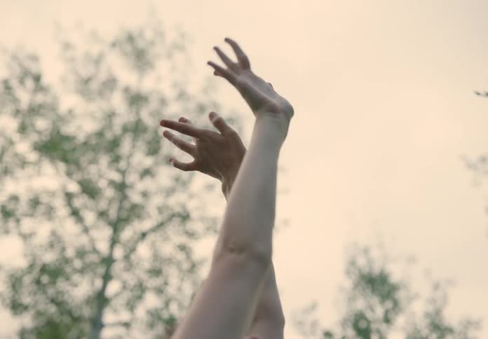 Closeup of a woman dancing with arms raised amidst nature