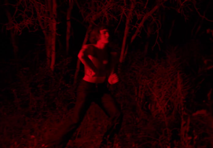Woman dancing at night in the forest with red light illuminating