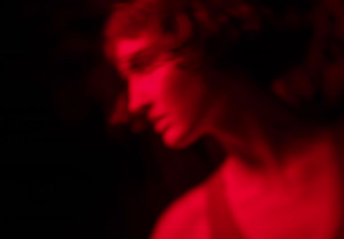 Portrait of a young woman dancing at night in a forest with red light beneath her