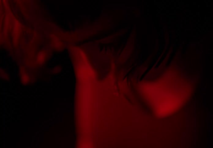 Young thin woman dances stretching under red light